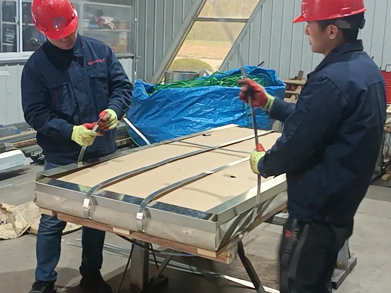 Workers strapping a stainless steel sheet pack