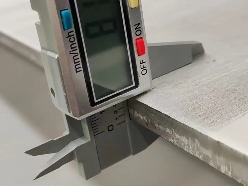 Checking stainless steel sheet thickness with a caliper