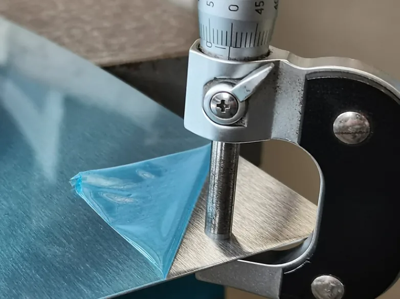 Checking stainless steel sheet thickness with a micrometer